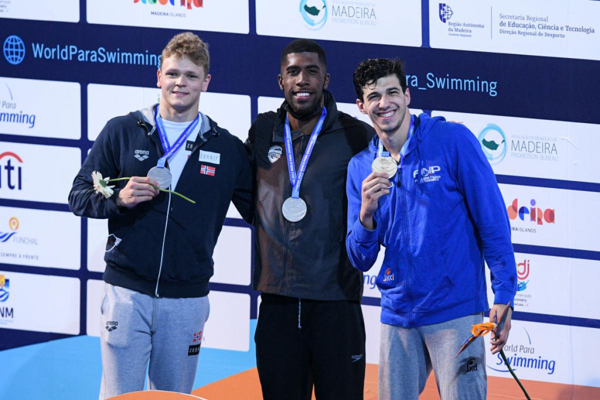 Three men standing on a podium with their medals