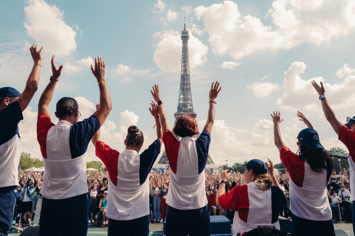 People wearing the colours of the French flag wave in front of the Eiffel tower in Paris.