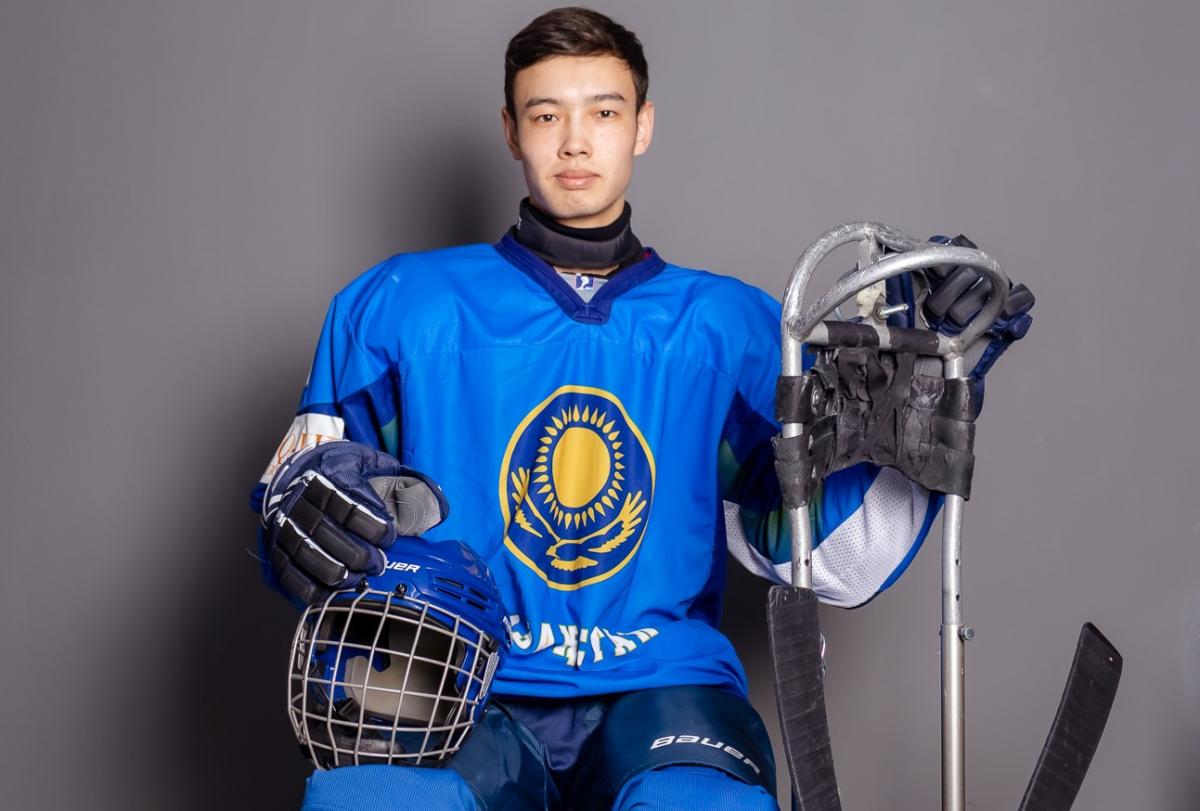 A man posing for a picture with Para ice hockey equipment