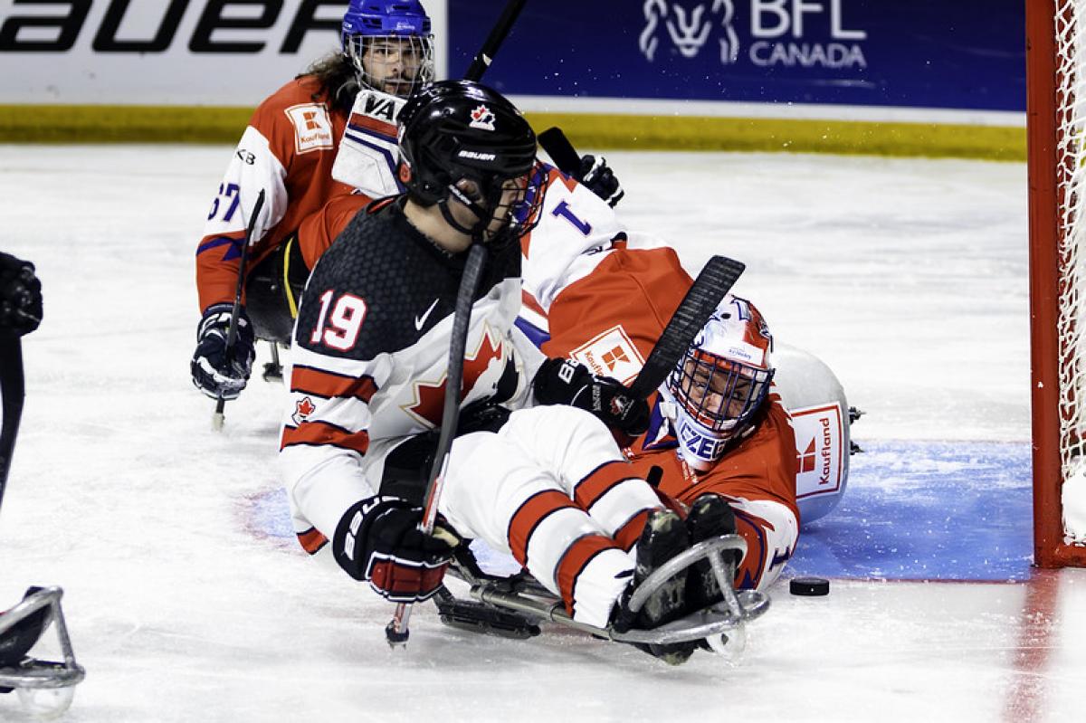 A Para ice hockey player trying to score in front of the goaltender