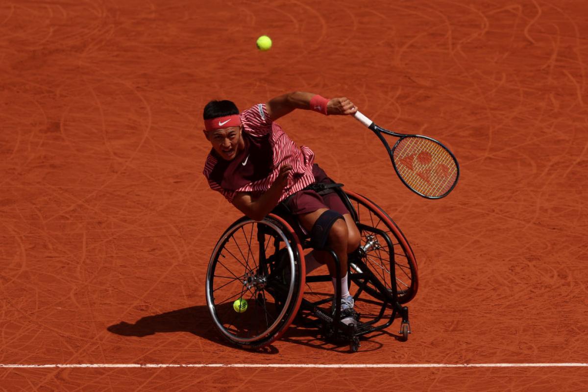 A male wheelchair tennis player swings his racquet during competition. 