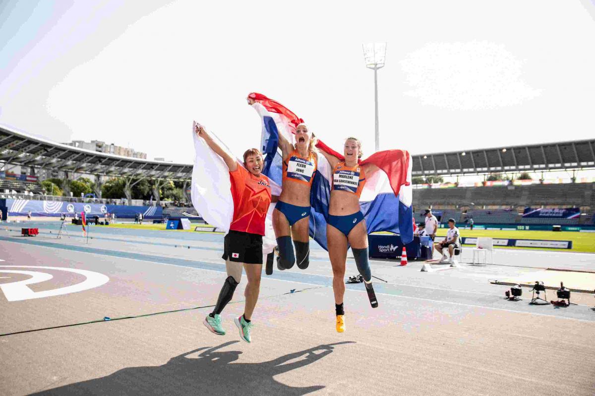 Three female athletes with prosthetic legs jumping