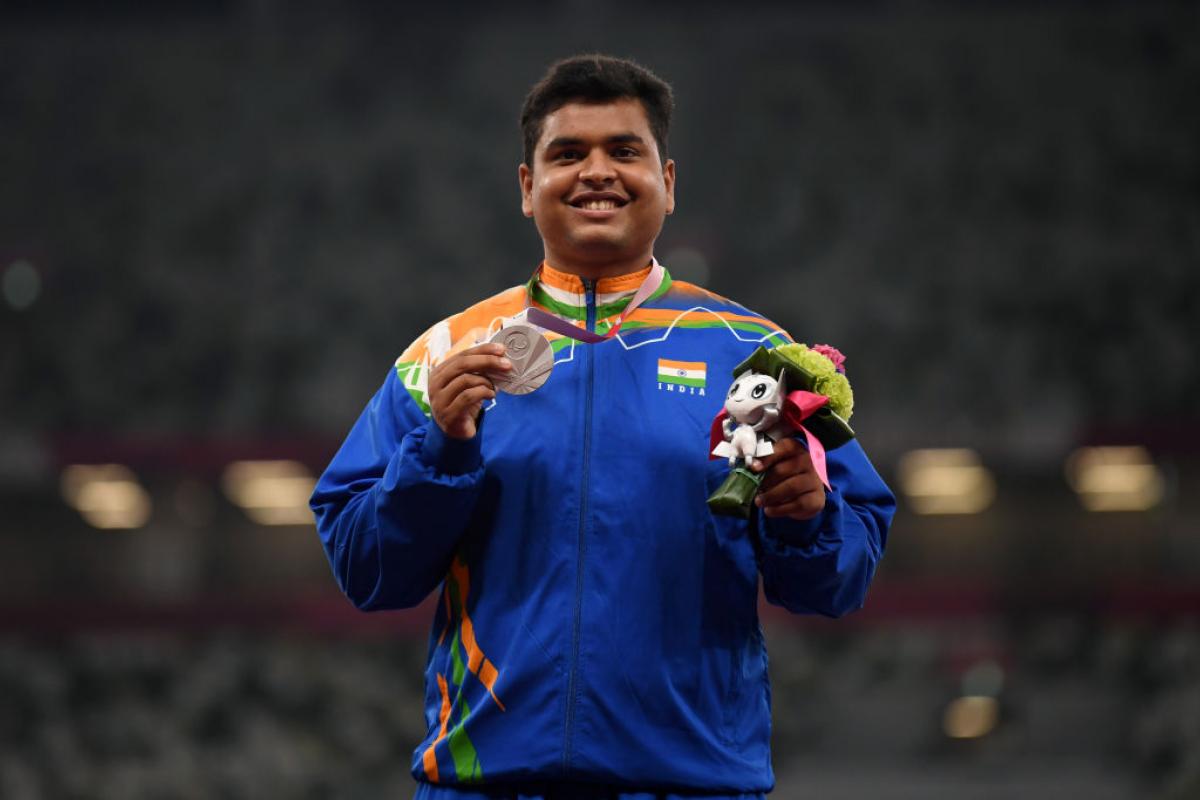 Yogesh Kathuniya smiling and holding up a Paralympic silver medal