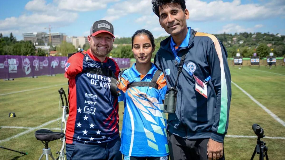 Three people, including a male and female archers, pose in front of a camera.