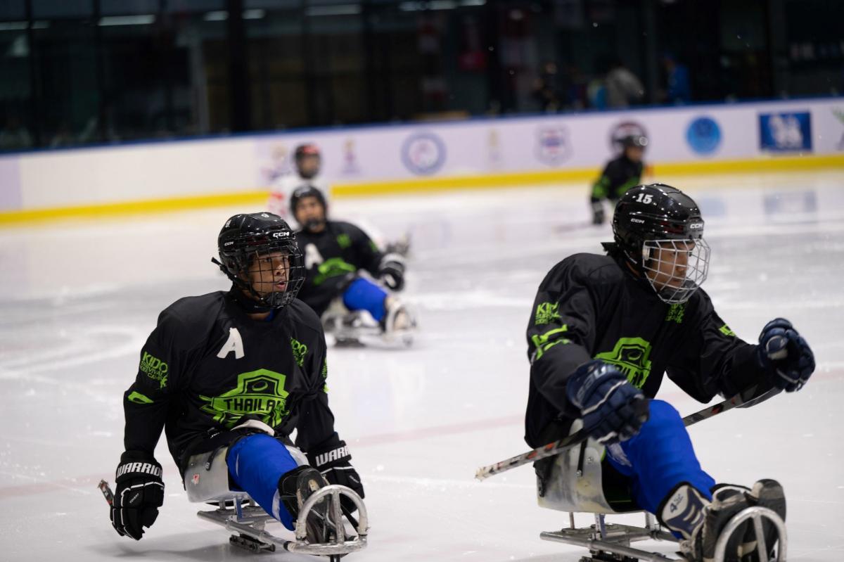 Three Thai Para ice hockey players in a game on ice