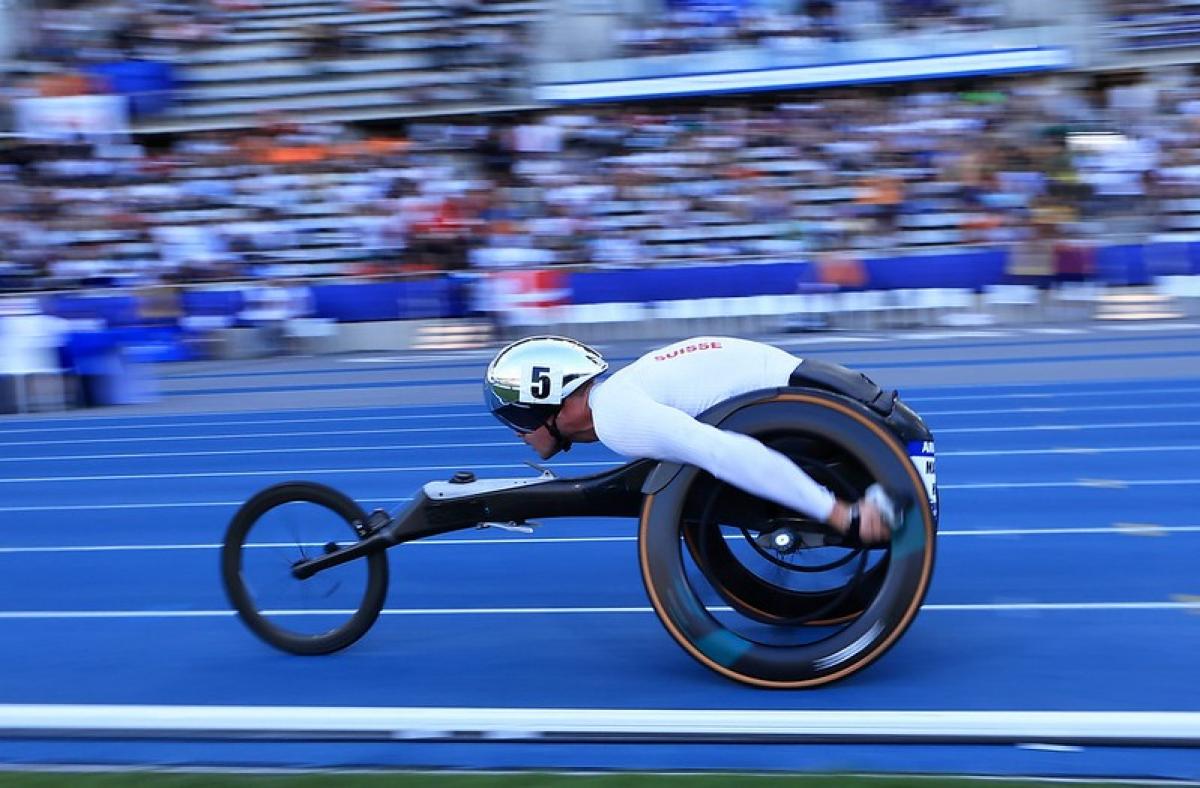 A male wheelchair racer running in front of the crowd