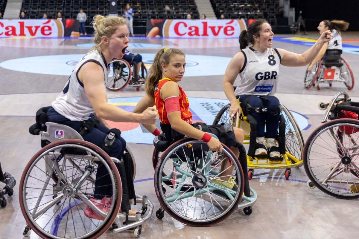 Three female wheelchair basketball players on court.