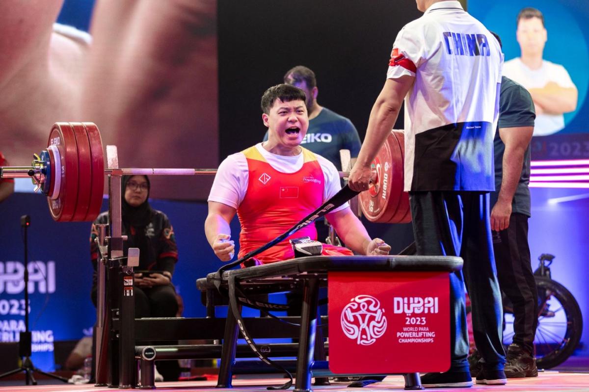 A male athlete celebrating on a bench press during a Para powerlifting event