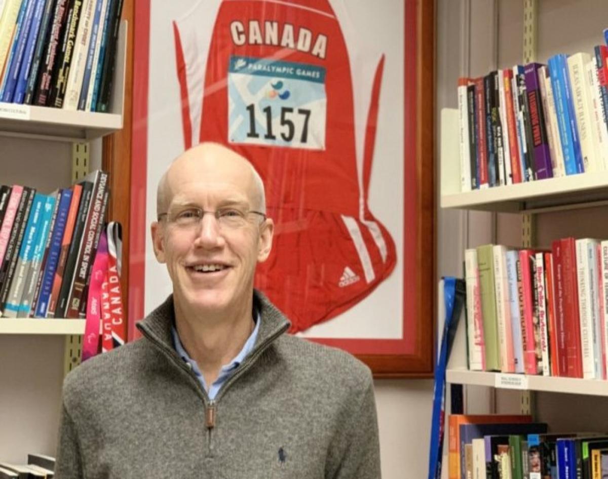 A man smiles in front of a book shelf.