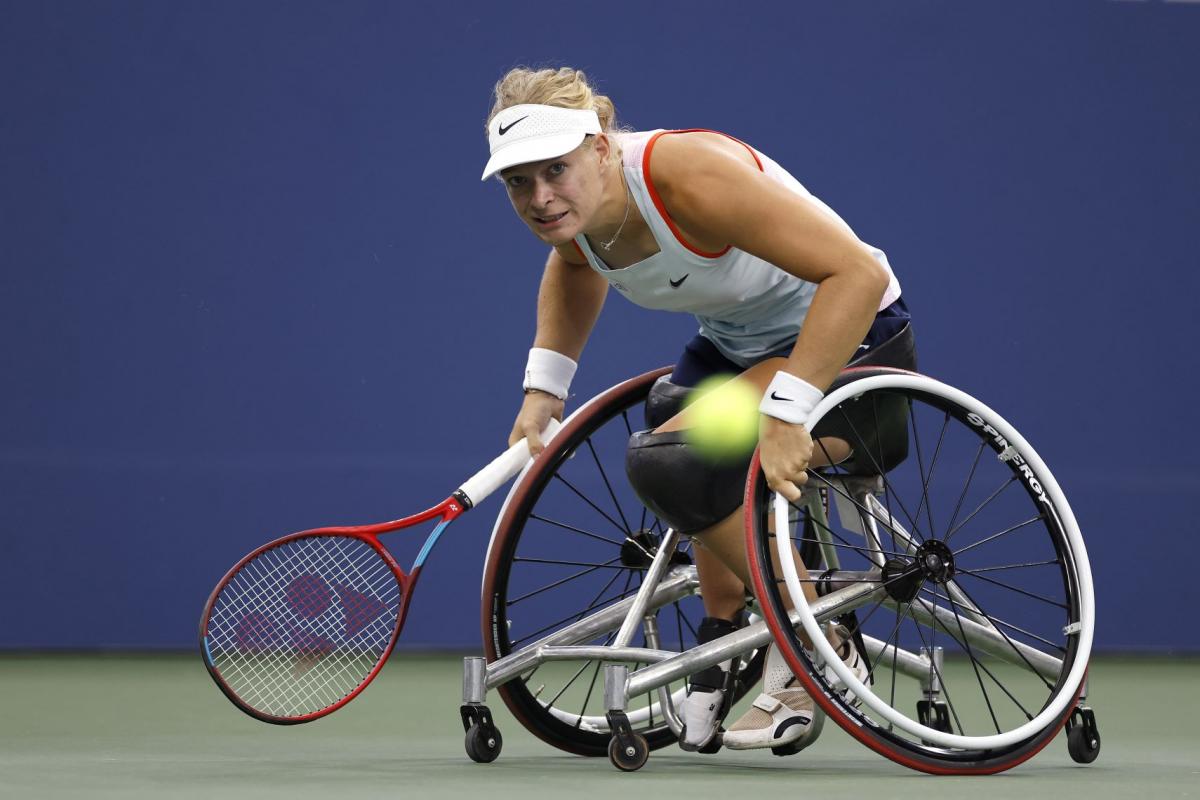 A female wheelchair tennis player hits a ball during ca game.