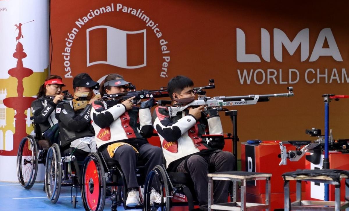 Four rifle shooters in wheelchairs in a shooting range