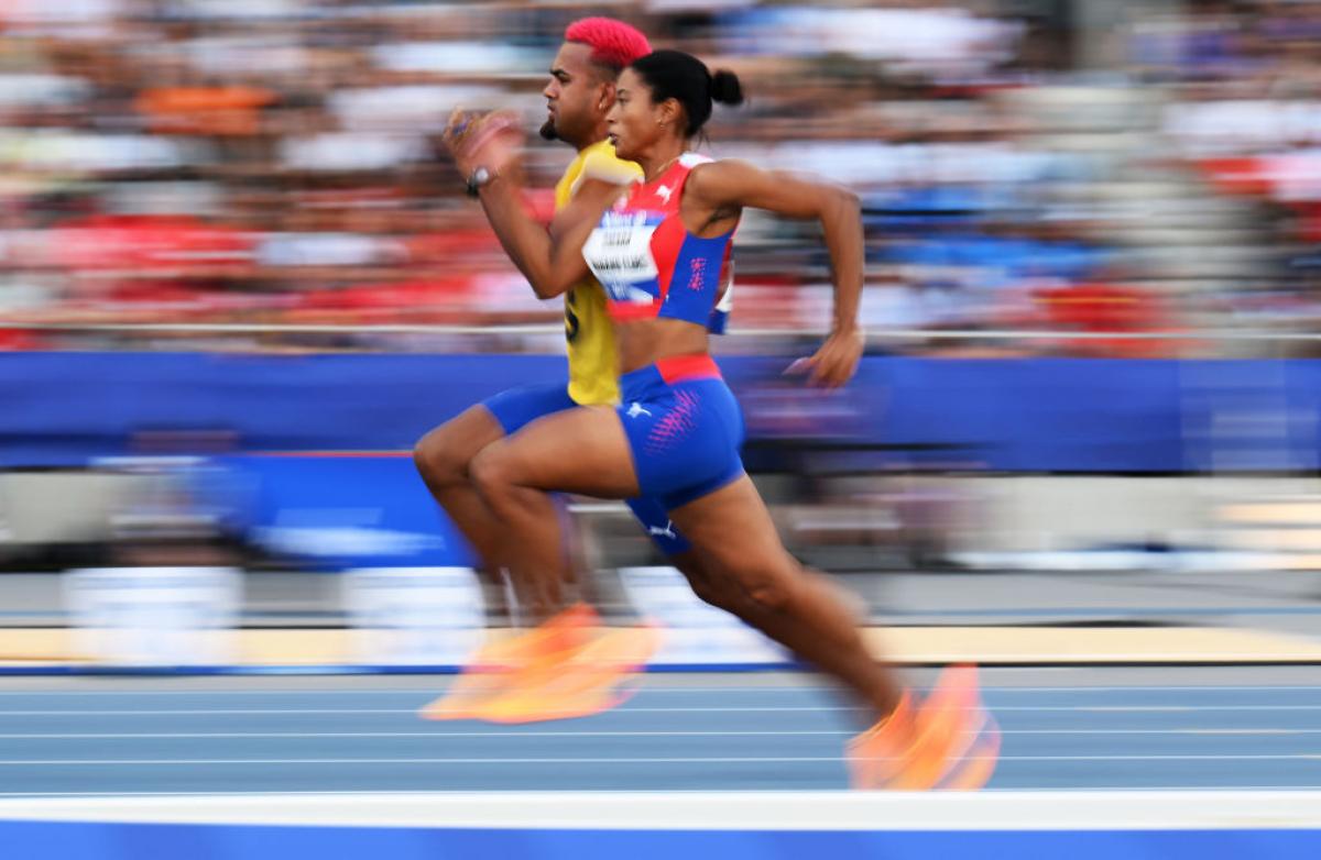 A female athlete running on a track next to her male guide