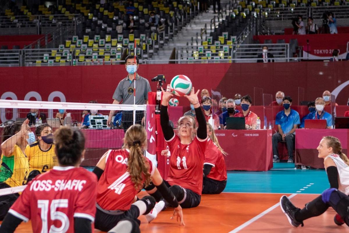 A female sitting volleyball athlete sets the ball during competition