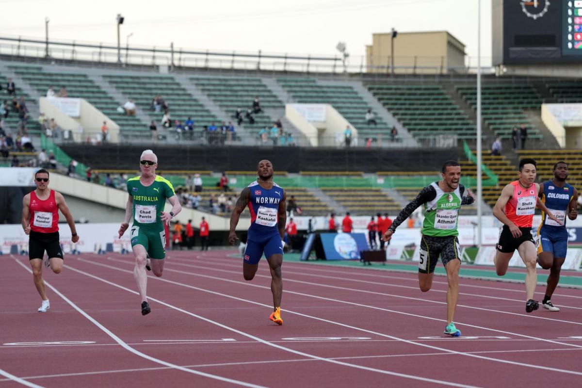 A man crossing the finish line in an athletics race ahead of five competitors