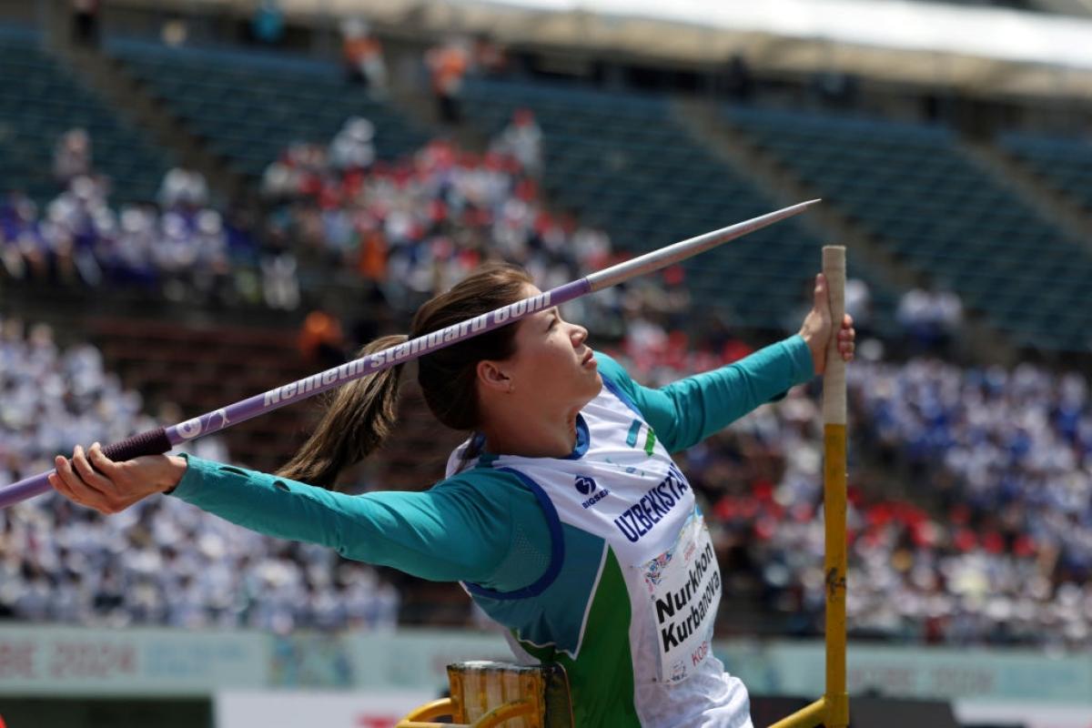 A female athlete throwing a javelin in a stadium