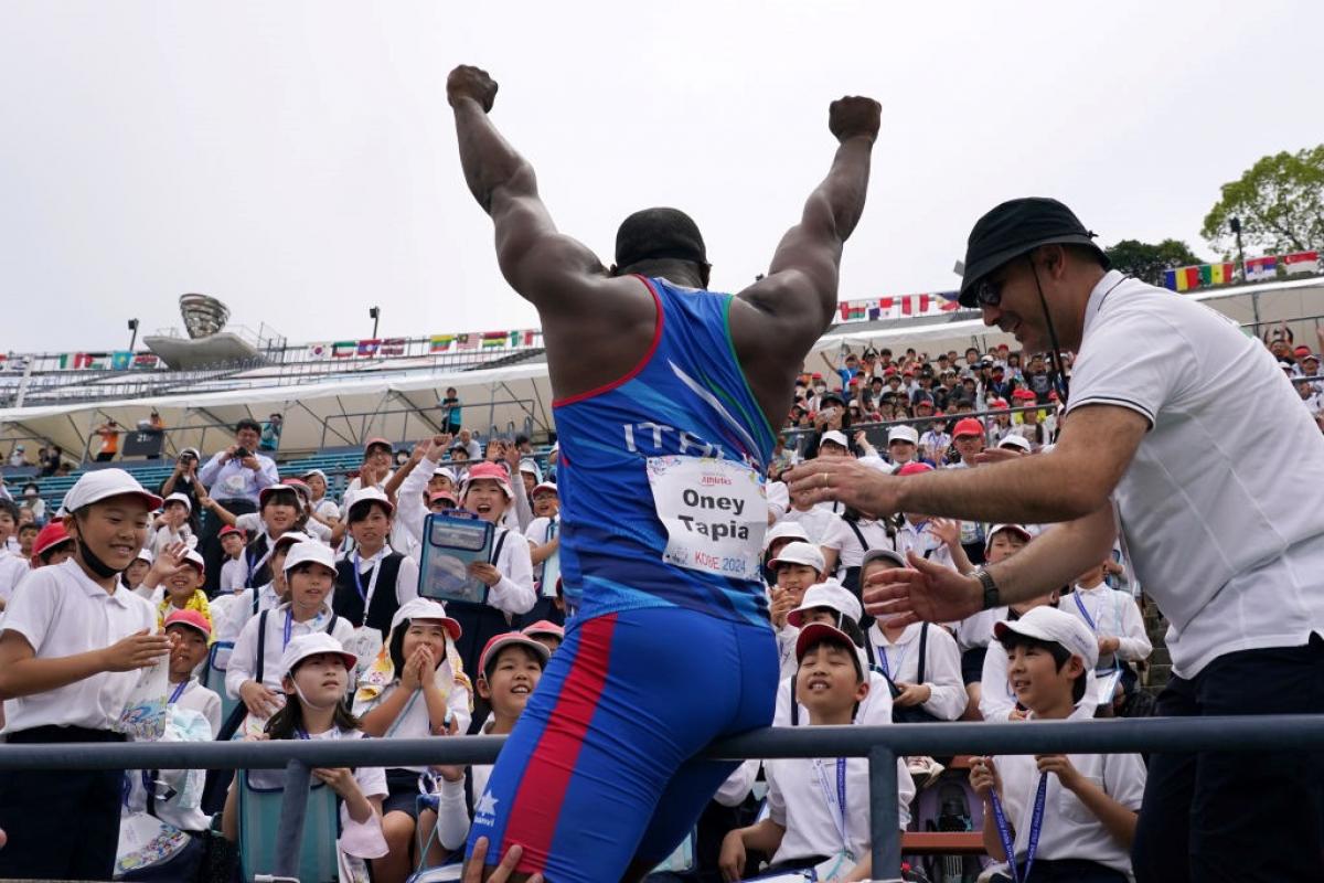 A man waving to a group of children in a stadium stand