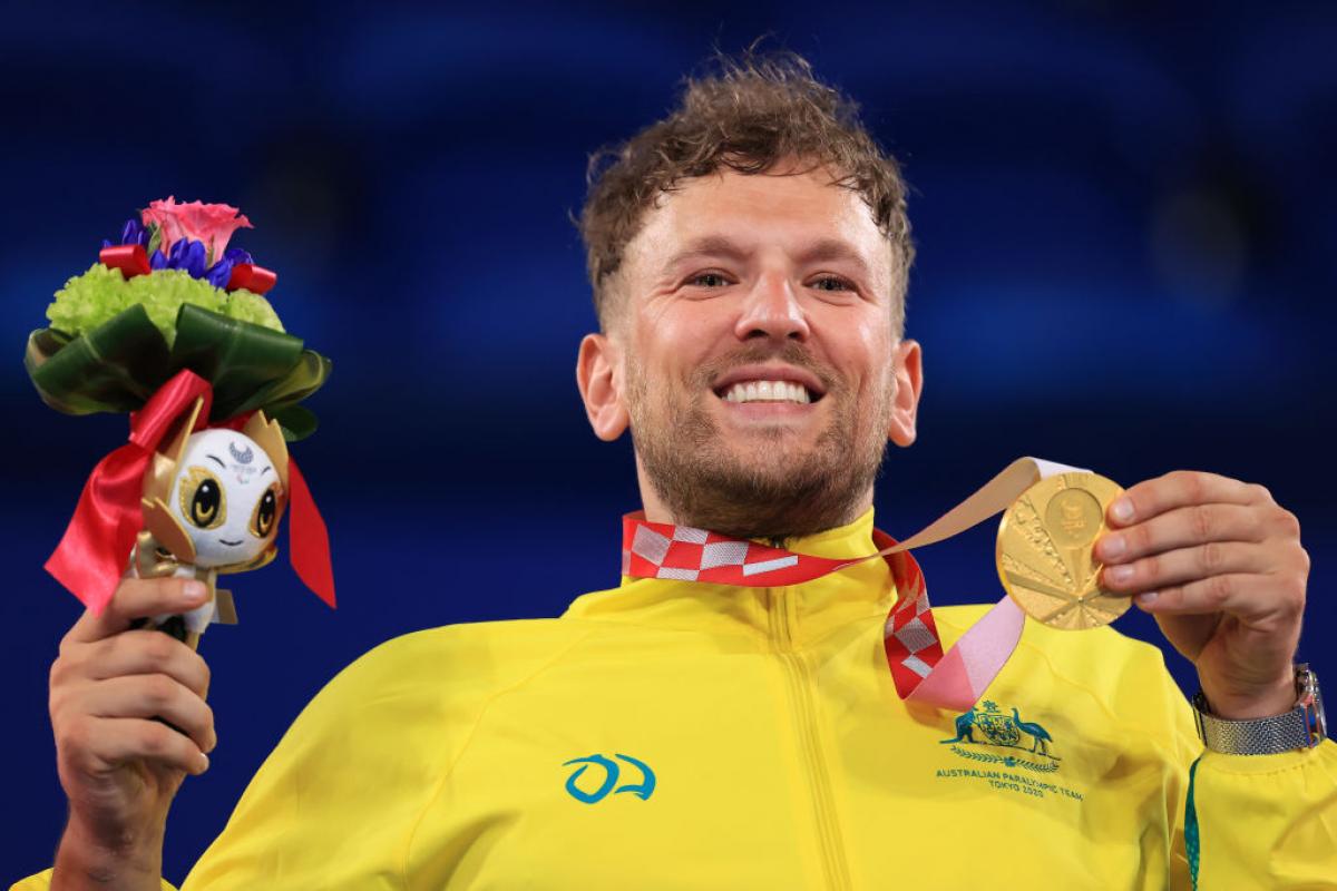Dylan Alcott, a male wheelchair tennis player, poses for a photo with a gold medal.