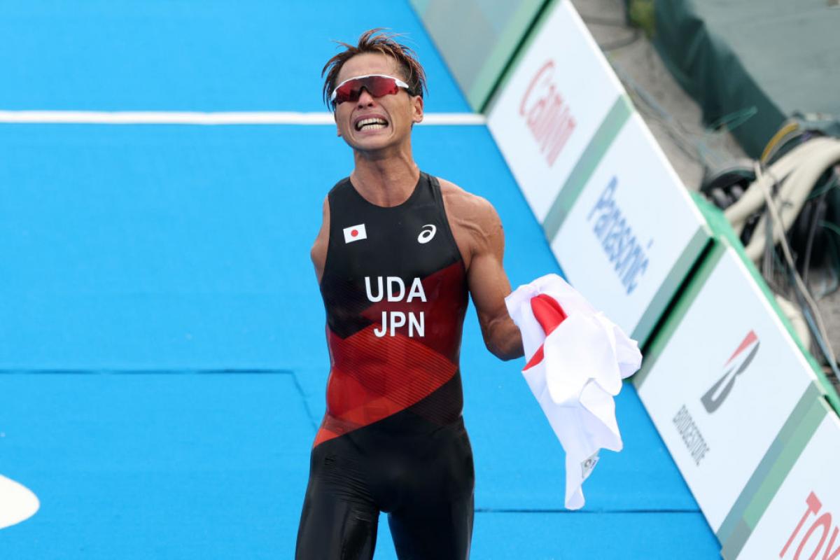 A male Para triathlon athlete reacts as he crosses the finishline