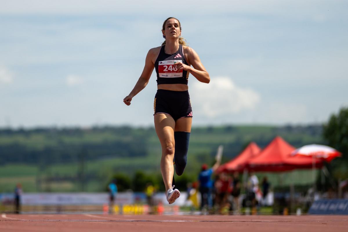 A female athlete with a prosthetic leg crossing the finish line