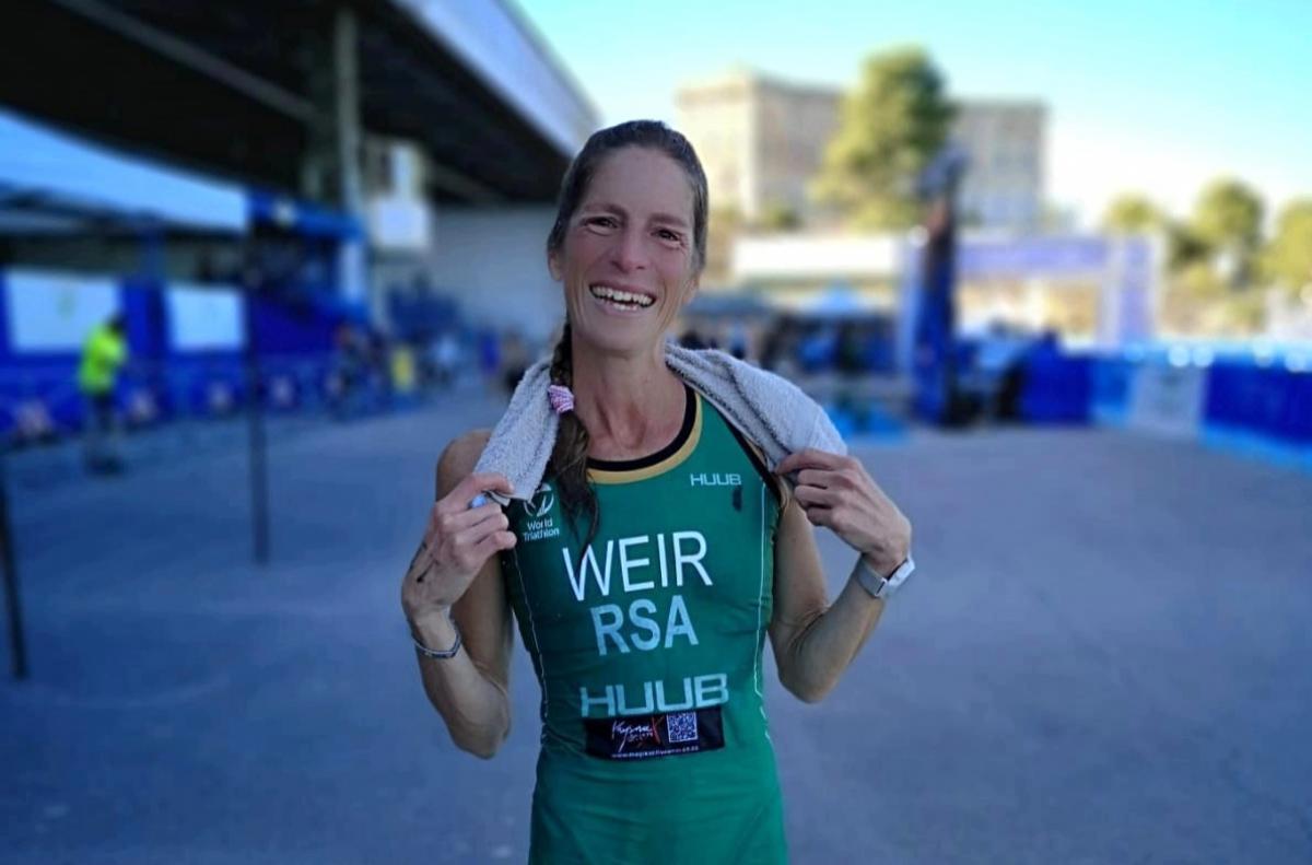 A female triathlete wearing South Afirca's green uniform smiles 