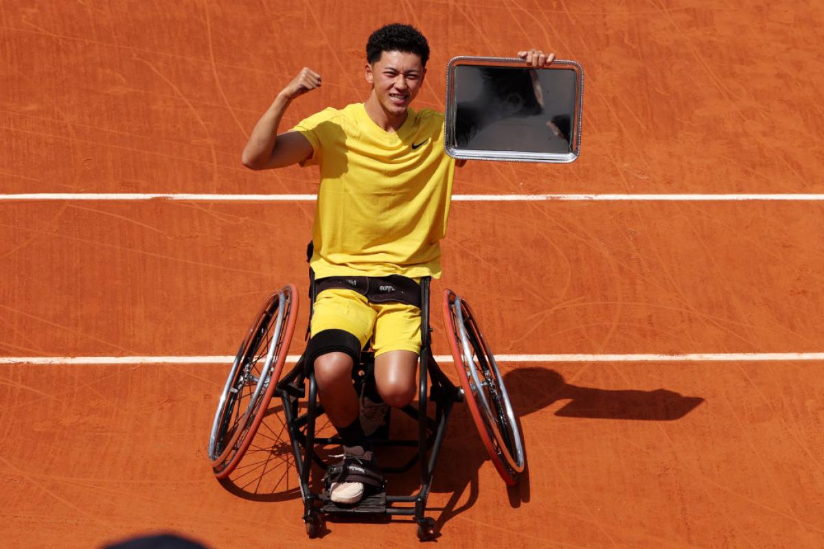 A male wheelchair tennis player poses for a photo after winning the 2024 French Open