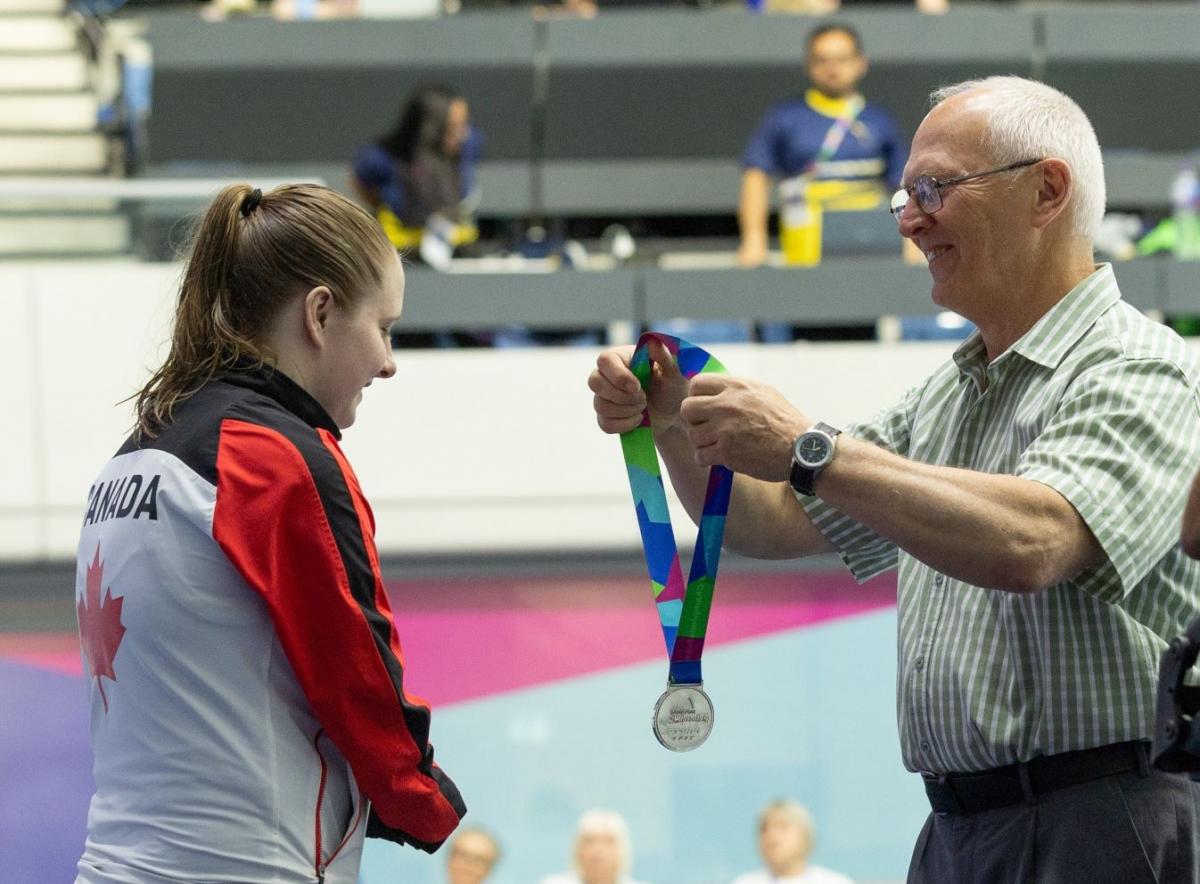 A man giving a silver medal to a female swimmer 