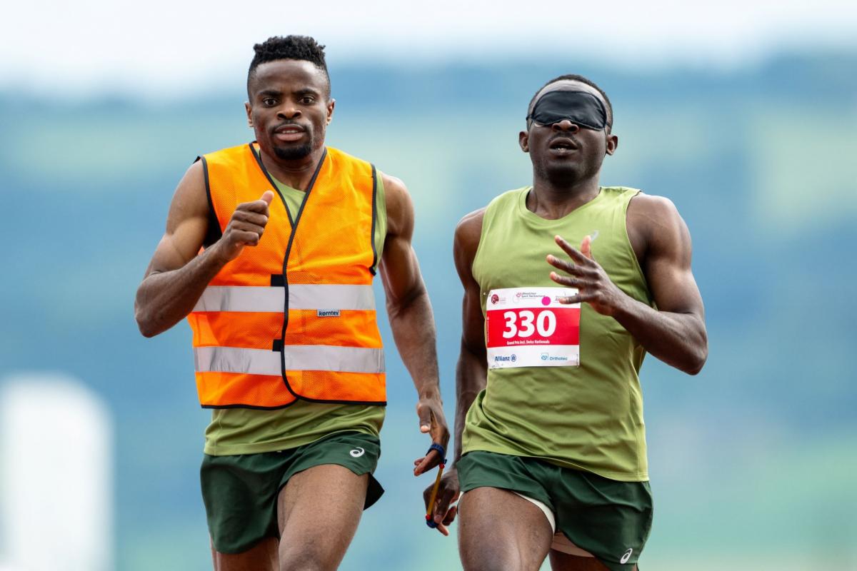 A male sprinter and his sighted guide competing