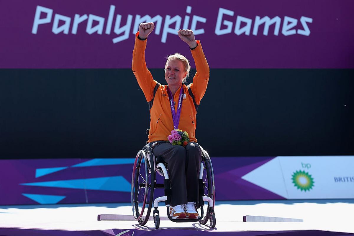 Esther Vergeer raises both hands to celebrate after receiving her gold medal.