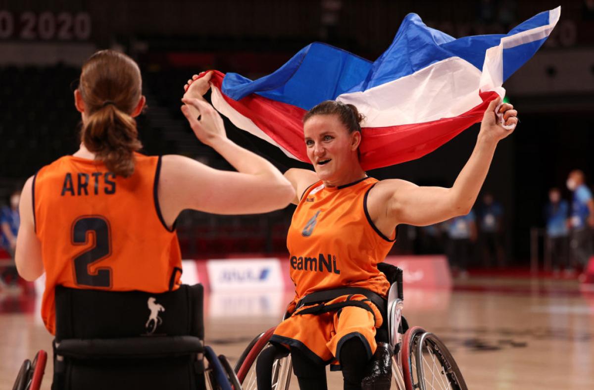 A female wheelchair basketball waves the Dutch flag to celebrate after a victory