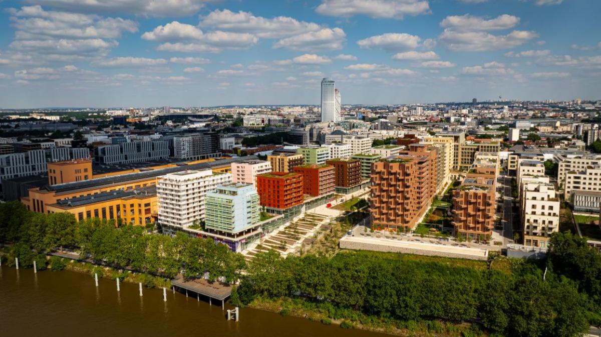 Photo taken from a drone shows the Paris 2024 Olympic and Paralympic Village. There are several buildings in front of a river.