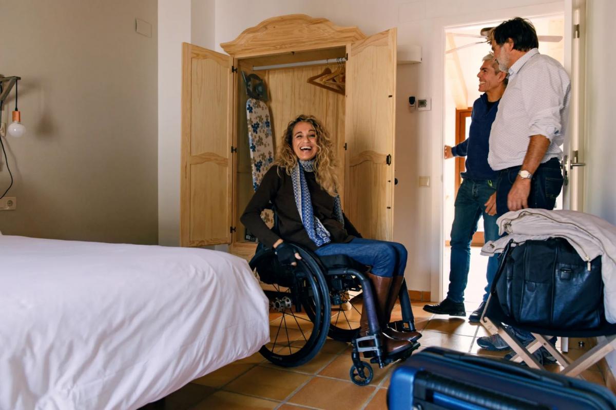 A female wheelchair user enters a bedroom and smiles