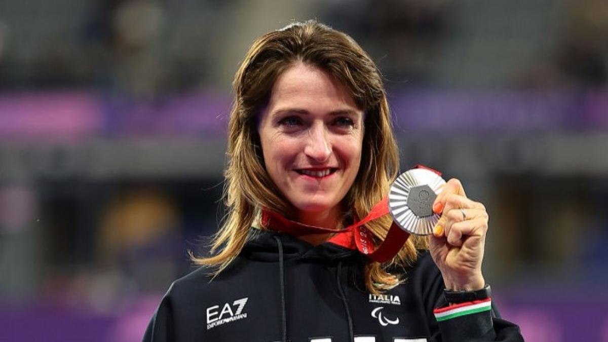 Para athlete Martina Caironi smiles and holds up a silver medal 