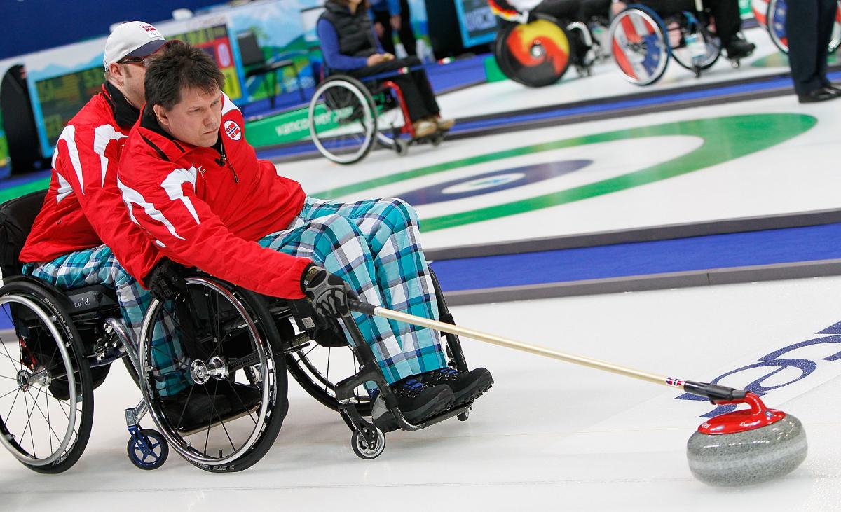 A picture of a man in a wheelchair playing curling