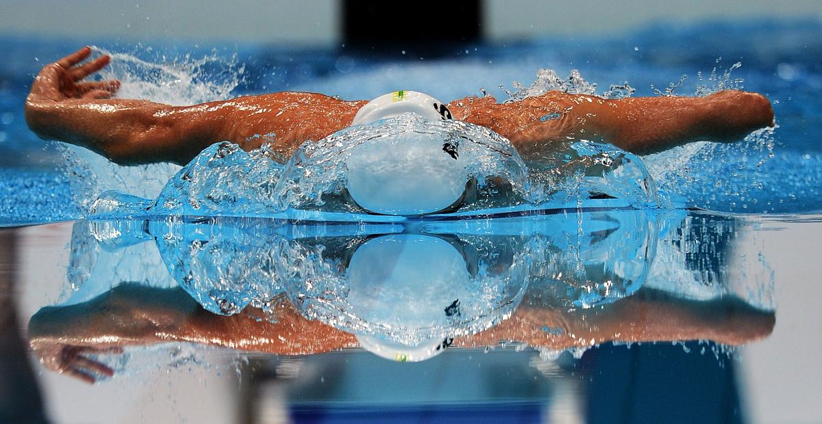 A picture of a man swimming with his both hands above the surface