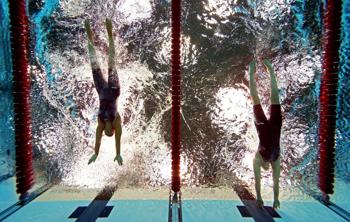 A picture of women in the pool touching the wall with their hands