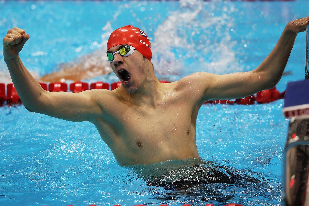 A picture of a man in the pool holding his hand up with clenched fist