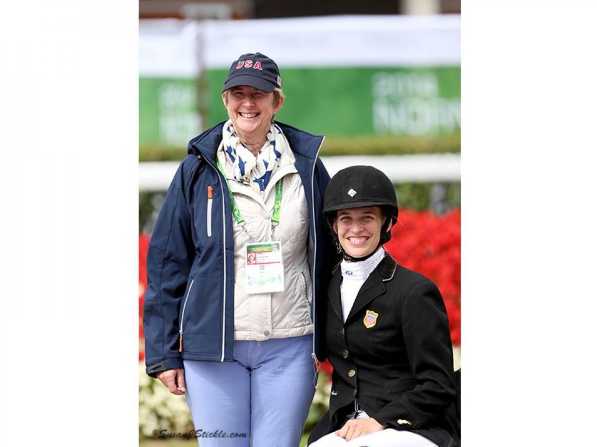 Two women posing for a photo, one with riding clothes