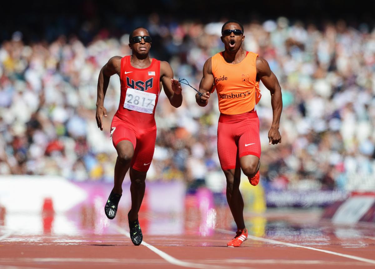 Runner and guide run in a full stadium