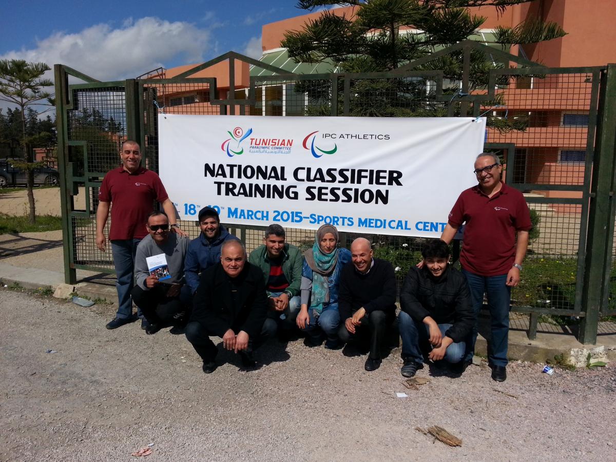 A group of people pose in front of an IPC Athletics banners in Tunis, Tunisia.