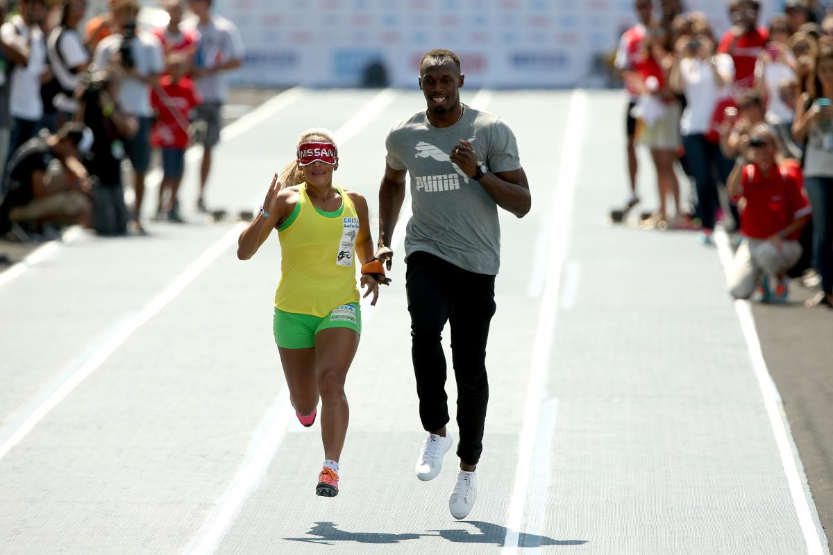 Brazilian Paralympian Terezinha Guilhermina runs with Usain Bolt of Jamaica as her guide during an exhibition in preparation for the Mano a Mano Athletics Challenge at the Jockey Club Brasileiro in Rio de Janeiro, Brazil.