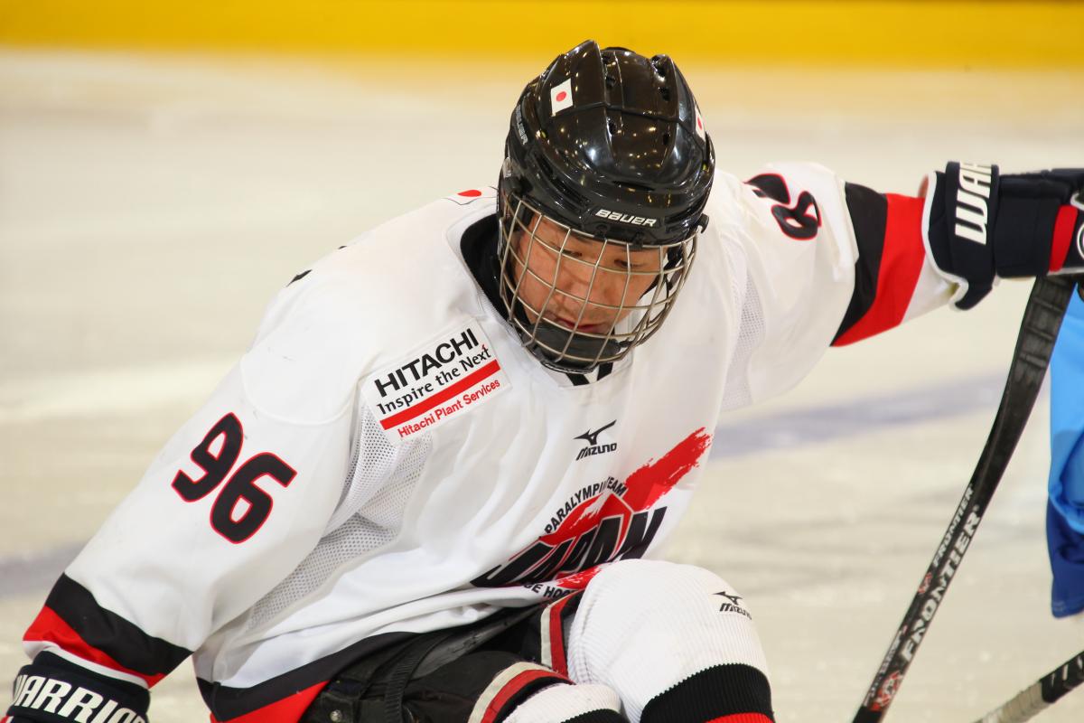 Man in white jersey and black helmet on a sledge