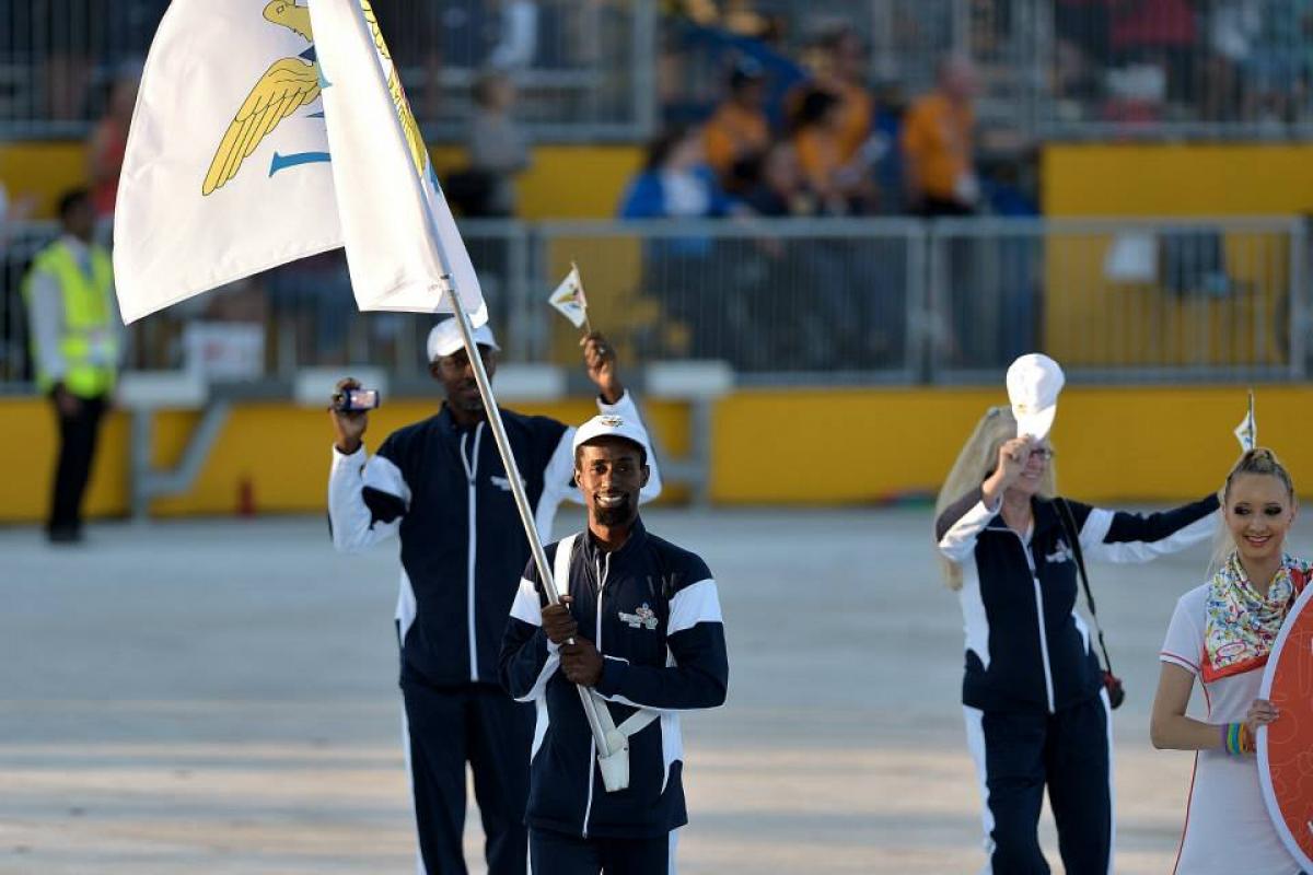 Man in a staduim, waving a flag followed by two other people