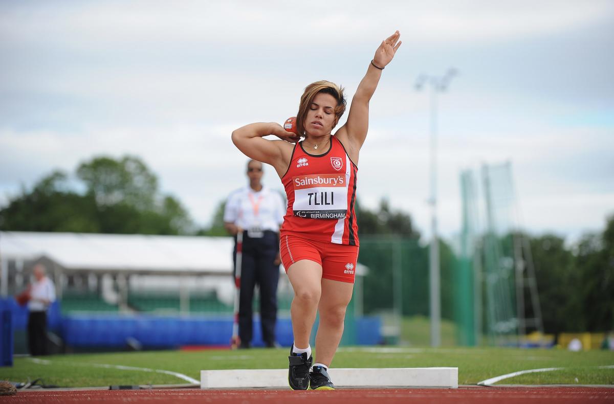 a female from Tunisia wearing red and competing in the shot put