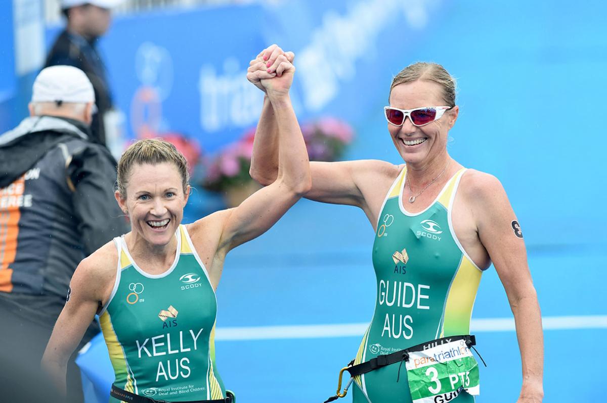 Two women in jerseys smiling and raising her arms