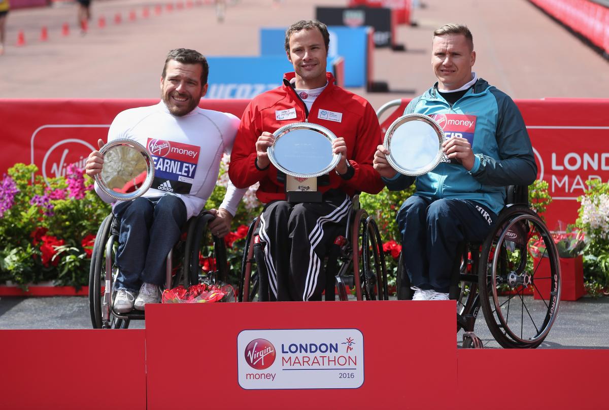 The podium finishers at the 2016 Virgin Money London Marathon - winner Switzerland's Marcel Hug of Switzerland (C), second place Australia's Kurt Fearnley (L) and third place Great Britain's David Weir.