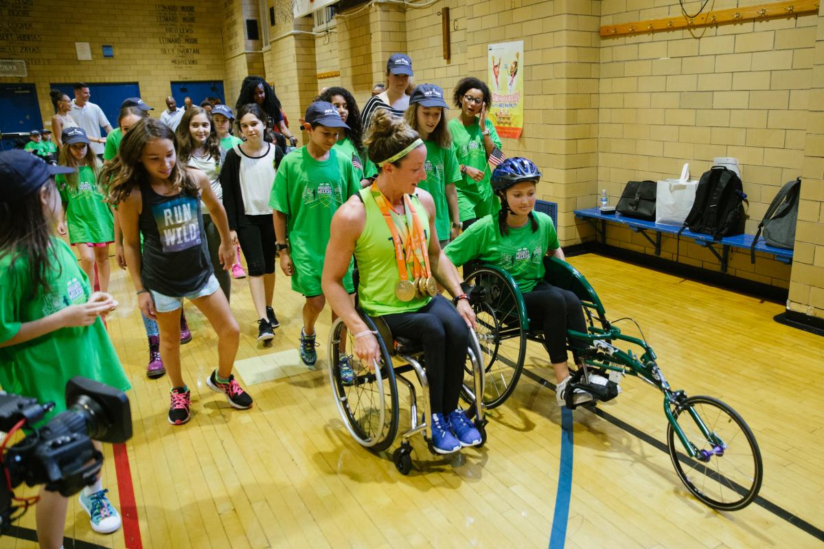 An athletes shows a young girl how to use a racing wheelchair