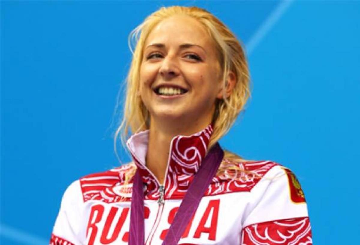 A picture of a woman standing with a silver medal around her neck