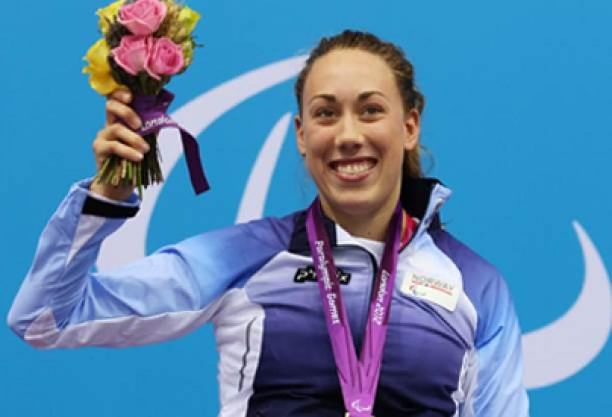 A picture of a woman in a wheelchair showing her gold hanging around her neck