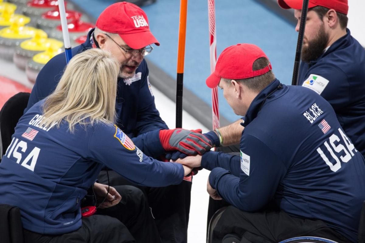 Group of people in blue jackets and wheelchairs forming a circle