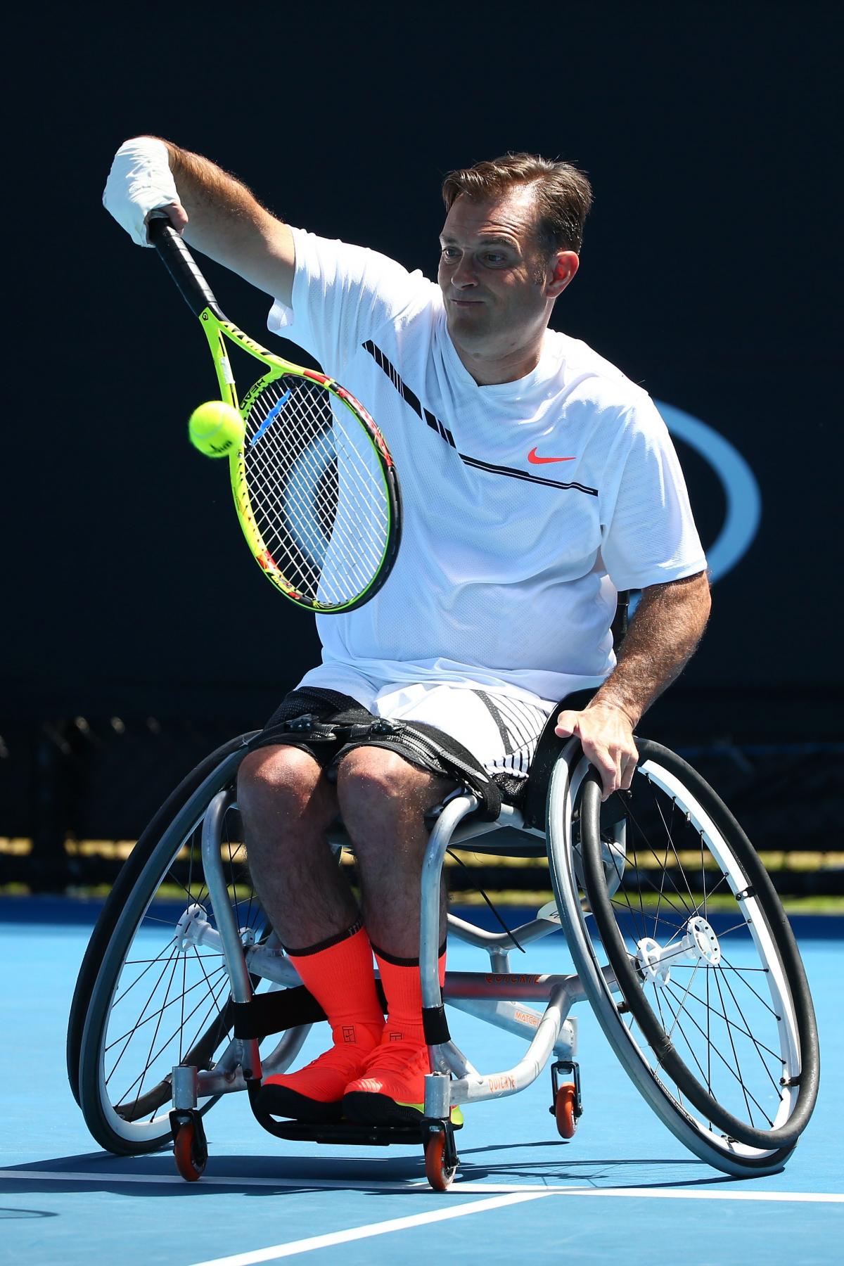 Man in wheelchair returns a tennis ball